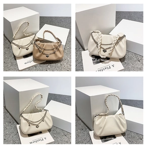 Détail de sacs plissés avec bandoulières tressées et breloques de chaînes en cœur