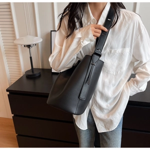 Detail view of black lychee grain bucket bag featuring an adjustable wide leather strap