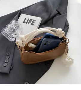 Sac à main marron avec anse blanche torsadée montrant l'espace pour téléphones et rouge