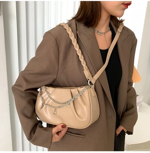 Détail du sac nuage beige avec plis, bandoulière tressée et double chaîne argentée
