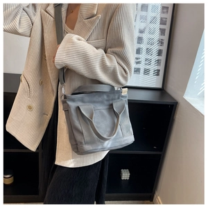 Detail showing the gray canvas tote bag with front pocket and detachable shoulder strap
