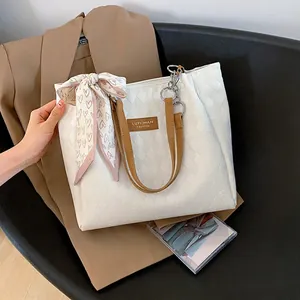 White quilted tote bag with brown handles and a heart print scarf for daily commuting