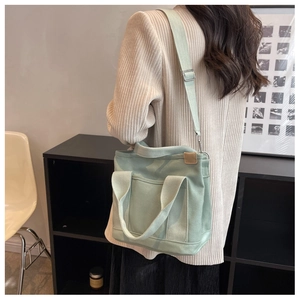 Mint green canvas tote bag shown worn as a crossbody by model for daily commute style