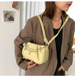Détail du sac plissé crème avec chaîne argentée à cœur et bandoulière en cuir tressé