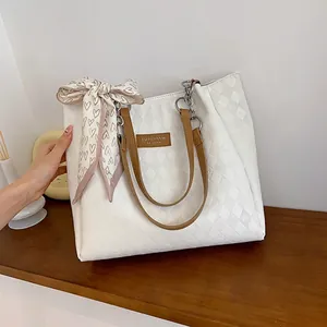 White quilted faux leather tote bag with brown handles and a decorative heart scarf