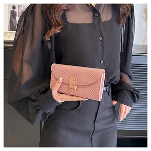 Pink crocodile pattern leather clutch wallet with flap closure held by a model