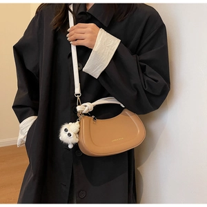 Détail du sac demi-lune marron avec poignée tressée blanche et charm en peluche