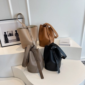 Litchi pattern leather bucket bags in four colors on a minimalist display stand