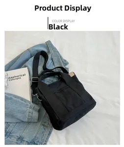 Detail of a minimalist black canvas tote bag with adjustable strap and front pocket