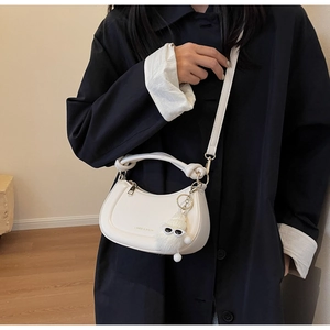 Détail du sac à main blanc en croissant avec breloque monstre et poignée nouée