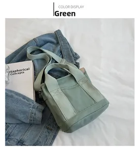 Flat lay of green canvas tote bag with adjustable strap and front pocket on fabric