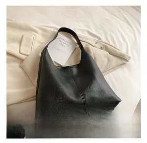 Detail shot of black pebbled leather texture and central vertical stitching on hobo bag