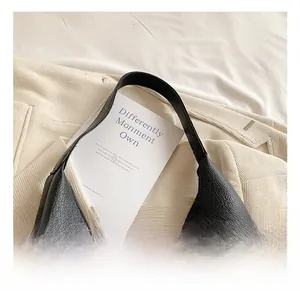 Close-up of black lychee grain leather tote bag showing detailed texture and handle attachment