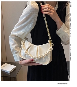 Close-up of white ruched cloud bag featuring oversized plastic chain and gold metal strap