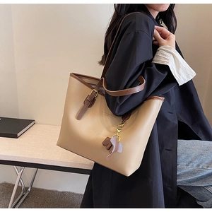 Close-up of beige large capacity tote bag with brown straps and elephant charm
