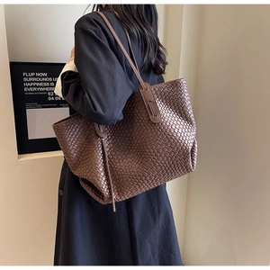Detail of dark brown woven tote bag showing the intricate leather weaving texture