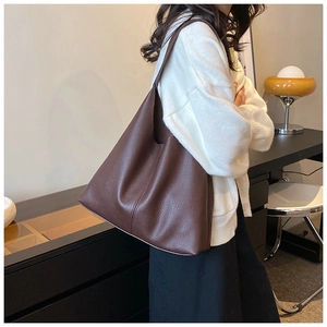 Detail of deep brown pebble grain leather hobo bag worn by model in cozy interior