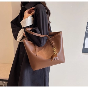 Close-up of brown leather tote bag texture with minimalist logo and elephant charm