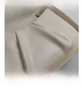 Close-up of the pleated faux leather texture and soft cloud design on a cream handbag