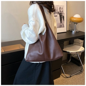 Detail of a large dark brown pebbled leather tote bag worn as a shoulder hobo bag