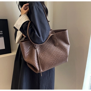 Close-up of dark brown woven leather texture on a spacious tote bag with shoulder strap