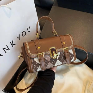 Brown leather Boston handbag with woven stitching and gold buckle in a luxury gift setting