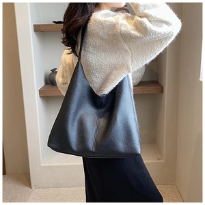 Detail of the high-quality lychee grain leather texture on a black tote bag carried by model