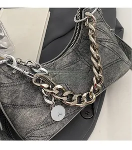Detail of grey denim shoulder bag featuring diamond stitching and thick silver chain strap
