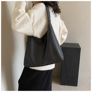 Detail of black large-capacity tote bag with pebbled leather texture and center seam