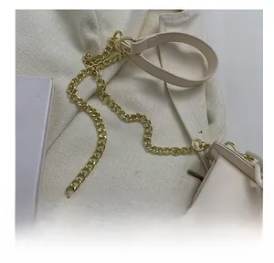 Detailed close-up of beige leather shoulder bag with golden chain and leather strap design