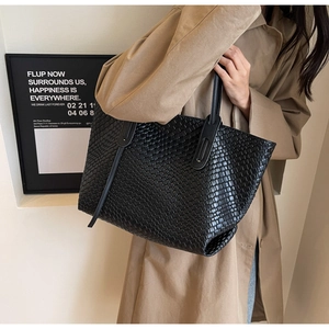 Detail of black woven leather tote bag showing large capacity and vintage texture