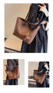 Detail view of a brown tote bag featuring a leather elephant charm and adjustable strap