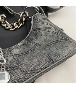 Close-up of vintage grey denim shoulder bag with geometric stitching and silver chain