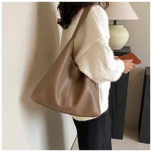 Deep brown lychee texture leather tote bag worn by a model in a cozy interior setting
