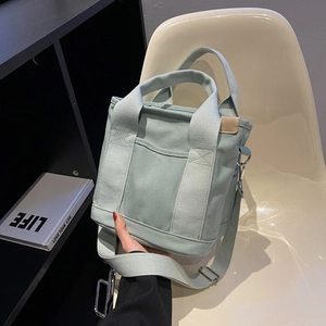 Mint green canvas tote bag with adjustable shoulder strap and front pocket detail