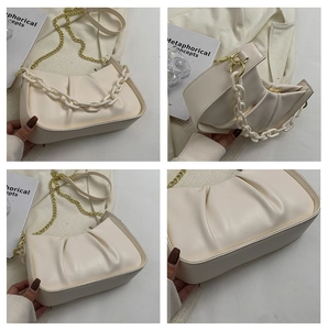 Close-up of pleated cloud bag with golden chain and resin decorative strap details