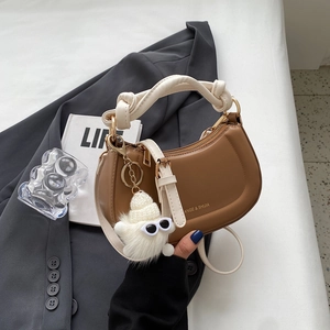 Sac à main demi-lune marron avec poignée nouée crème et breloque en peluche sur veste