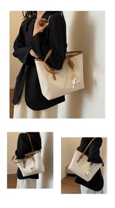 Detail of white PU tote bag with brown trim and cute metal elephant charm decoration