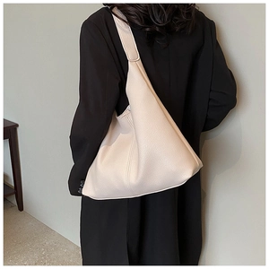 Close-up of minimalist beige hobo bag with textured litchi pattern and wide shoulder strap