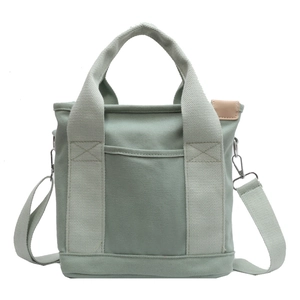 Minimalist light green canvas tote bag with adjustable shoulder strap and front pocket