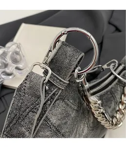 Close-up of grey denim texture, sturdy silver metal chain and zipper detail on bag