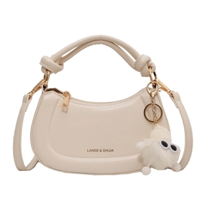 Sac hobo crème avec poignée nouée et breloque monstre en peluche sur fond blanc