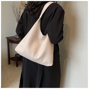 Detail of a large off-white leather tote bag with lychee texture shown on the shoulder