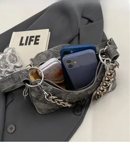 Detail showing spacious interior of gray denim chain bag holding two smartphones