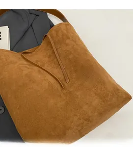 Close-up of brown suede tote bag with soft fabric texture and decorative straps