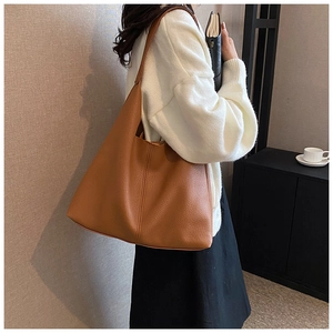 Detailed view of the brown lychee pattern leather tote bag worn on a woman's shoulder