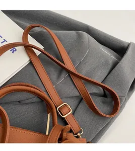 Detailed close-up of the adjustable brown pebbled leather shoulder strap with gold buckle