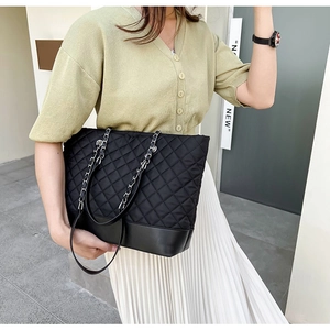 Détail d'un sac cabas noir matelassé avec bandoulière en chaîne et coutures précises