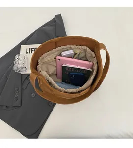 Top view of large brown suede bucket bag showing spacious interior with canvas drawstring bag