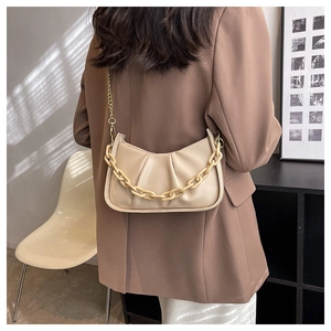 Detail of beige pleated cloud bag with gold chain and acrylic strap on shoulder